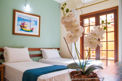 帕拉蒂Pousada Villa Verano的一间设有两张床的房间和白色花瓶