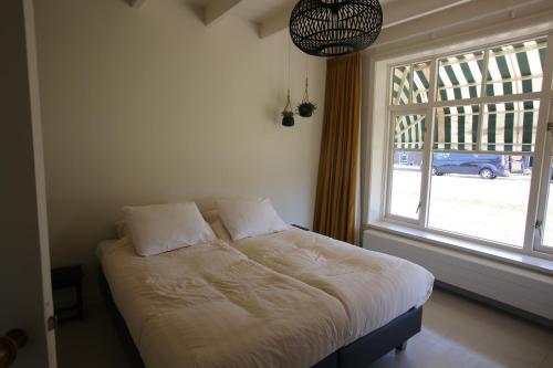 圣尼古拉斯哈Recreatieappartement BoerdeRijlst - De Kamer的一张位于带大窗户的房间内的床铺