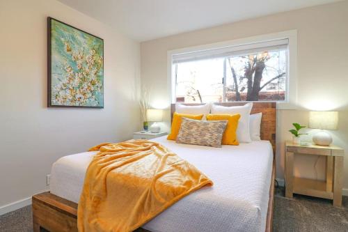 博伊西Condo 24! Prized Location. Modern! Bright! Enjoy!的一间卧室配有带橙色枕头的床和窗户。