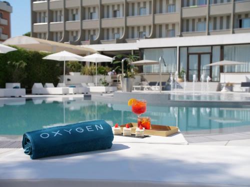 里米尼Oxygen Lifestyle Hotel的池畔桌子,边喝一杯,边喝一杯