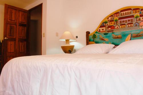瓦哈卡市Casa Rosa Mexicano的卧室配有一张白色床,墙上挂有绘画作品