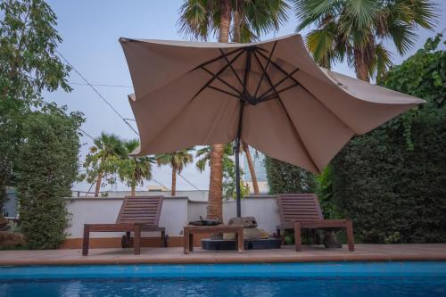 利雅德شاليه خاص的游泳池畔的一把遮阳伞和两把椅子
