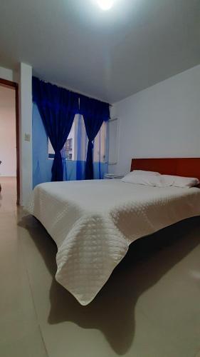 锡帕基拉Apartamentos Turisticos EL ZIPA的卧室配有白色床和蓝色窗户