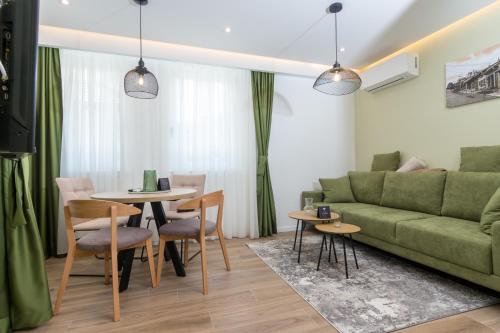 萨拉热窝Mayisa Apartments的客厅配有绿色沙发、桌子和椅子
