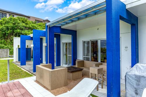 恩纳Hermit Hills Okinawa  -SEVEN Hotels and Resorts-的蓝色柱子的房子和庭院