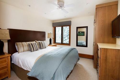 阿斯潘3 Bedroom Mountain Residence In The Heart Of Aspen With Amenities Including Heated Pool, Hot Tubs, Game Room And Spa的一间卧室配有一张大床和电视