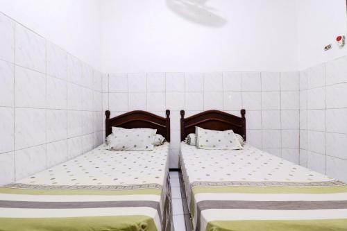 SukodonoHotel Gajah Mada的白色瓷砖客房内的两张单人床