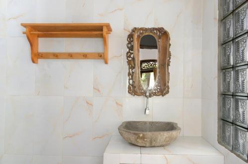 吉利特拉旺安Warna Beach Hotel的一间带石制水槽和镜子的浴室