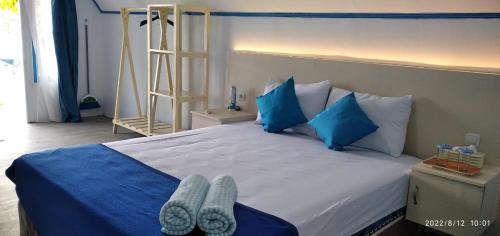 Ngurblut3 Maria Cottage的一间卧室配有一张大床,提供蓝色枕头和鞋子