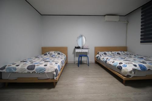 首尔Bunk Backpackers Guesthouse的配有两张单人床的客房配有一张桌子和一张四柱床。