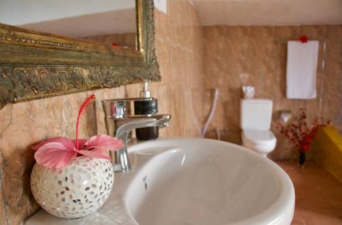 桑给巴尔The House of Royals的浴室水槽,花瓶里装有粉红色的花朵