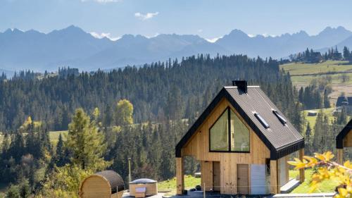 Białka TatrzanskaSielsko Anielsko Tatry Jacuzzi & Sauna的山丘上以山为背景的房子