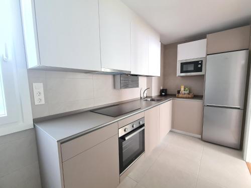 伊伦Apartamento Nicores Bidasoa的厨房配有白色橱柜和不锈钢冰箱