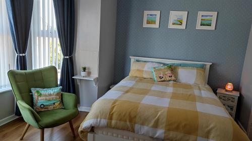 班多伦Luxury 3 bedroom house with peaceful garden, sleeps 6 and 2 mins to beach的一间卧室配有一张床和一把绿色椅子