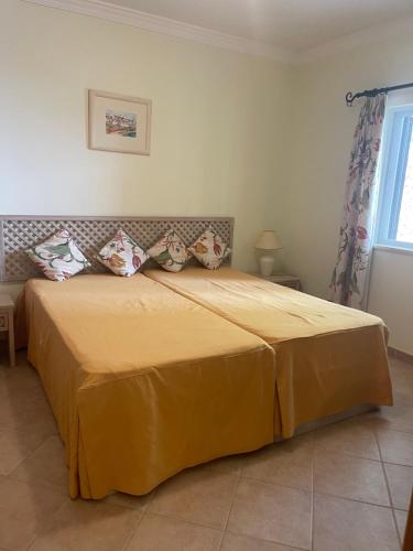 阿尔布费拉Lovely 2 Bedroom Home inside a Resort in Albufeira的卧室配有一张带黄色床单和枕头的大床。