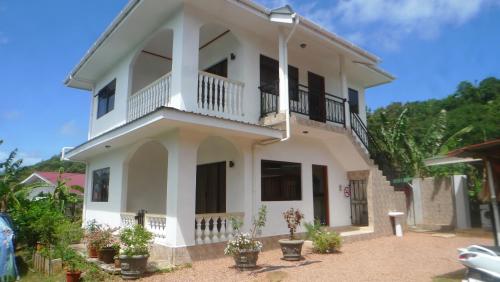 贝圣安那Belle Rose Vue guest house的带阳台和盆栽植物的白色房屋