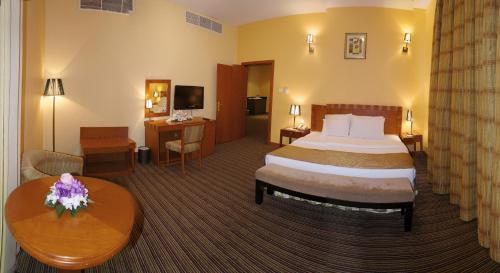 艾恩Al Massa Plus Hotel的酒店客房配有一张床铺和一张桌子。