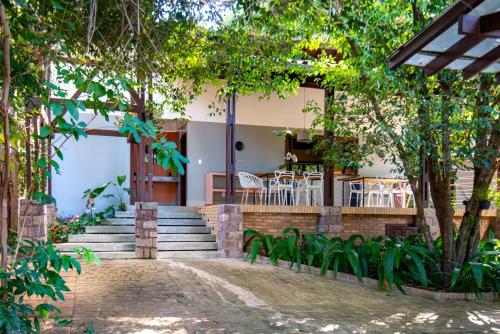 伦索伊斯Casa Antônia - Pousada Boutique的房屋设有楼梯和桌子,树木繁茂