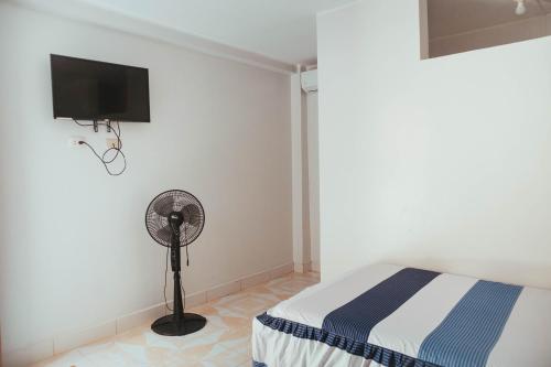 YurimaguasHospedaje Garcilazo的一间卧室配有一张床、一个风扇和一台电视。