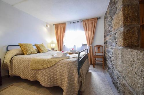 阿尔德亚达斯Casinha da Deolinda的一间卧室设有一张床和石墙