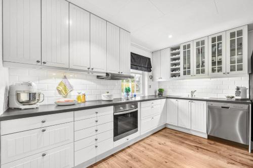 特隆赫姆private room in shared apartment的白色的厨房铺有木地板,配有白色橱柜。