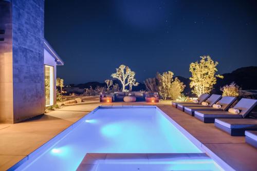 约书亚树Amaru Muru - Luxury Retreat with Pool/Hot Tub/Yoga的后院,晚上设有游泳池