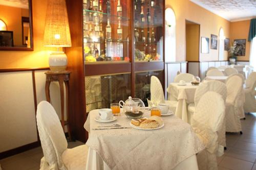 Lariano奈斯波罗多罗酒店的用餐室配有白色的桌子和白色的椅子