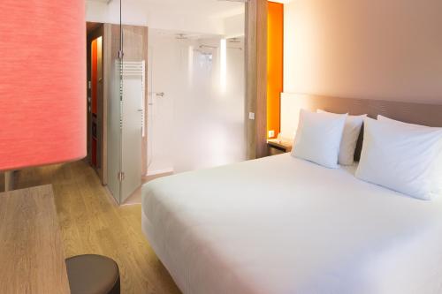 勒梅尼尔阿姆洛巴黎鲁瓦西大洋洲酒店的卧室配有带白色枕头的大床