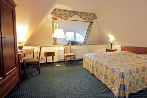 奥伊宾Parkhotel Oybin的配有一张床、一张书桌和一扇窗户的酒店客房