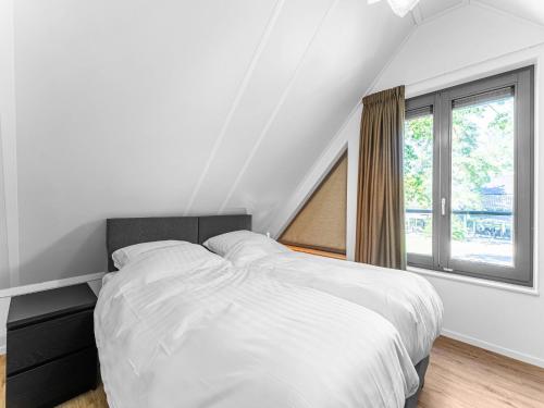 洛赫姆Modern holiday home in Lochem with private garden的白色的卧室设有一张大床和一个窗户