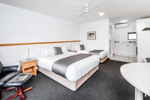 纳尔逊棕榈汽车旅馆的一间卧室配有两张床、一张桌子和一把椅子