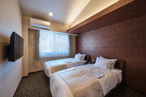 京都HOTEL ARROWS ARASHIYAMA的酒店客房设有两张床和电视。