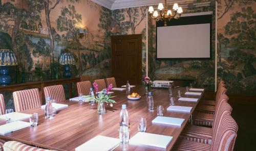 阿什伯恩Wildhive Callow Hall的一间会议室,内设一张长桌和一个投影屏幕