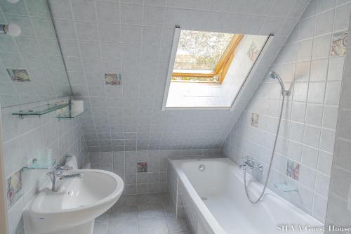 博尔斯克SILVA Guest House - dom wczasowy, tenis, basen, balia i sauna的白色的浴室设有水槽、浴缸和窗户。