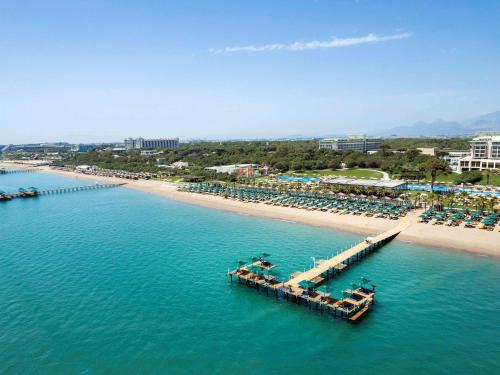 贝莱克Rixos Premium Belek - The Land of Legends Access的海滩空中美景,设有椅子和码头