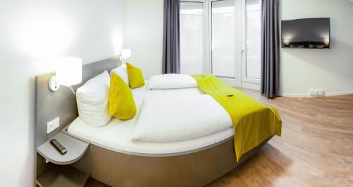 马格德堡Das ELB Boardinghouse Hotel Restaurant的一间小卧室,配有一张带黄色枕头的床