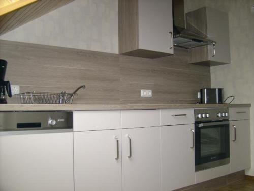 布兰肯海姆Ferienwohnung-Freuen的厨房配有白色橱柜和炉灶烤箱。