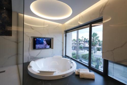马里纳·迪·瓦尔卡图罗贝拉维斯塔酒店 的带电视的浴室内的白色大浴缸