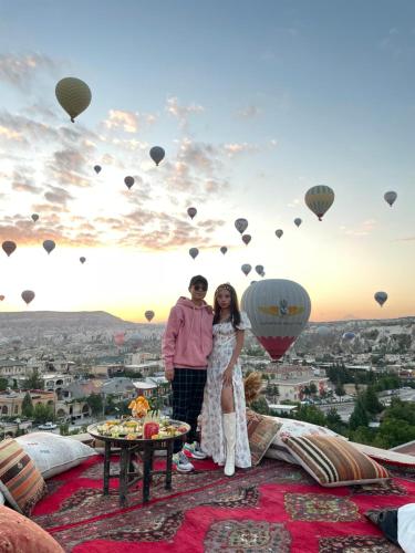 格雷梅Doors Of Cappadocia Special Cave Hotel的一对夫妇站在山顶,坐着热气球