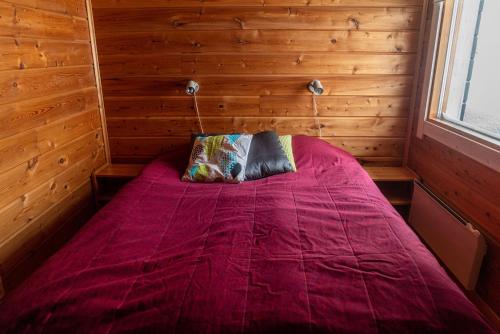 穆奥尼奥Tunturilapin Tuvat的木制客房内的一间卧室配有一张紫色的床