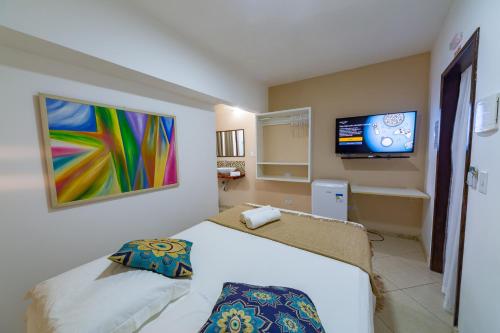 普拉亚多Praia do Forte Suites的一间卧室配有一张床和一台平面电视