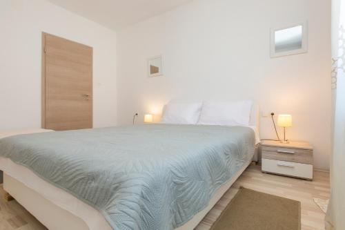 布泽特Apartmani Xenia & Desiderio的白色卧室设有一张大床和木地板