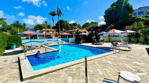 纳塔尔Yacht Village Natal Prime的度假村的游泳池配有椅子和遮阳伞