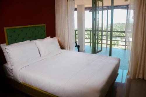特里凡得琅Aanandakosha Ayurveda Retreat的卧室配有白色的床和大窗户