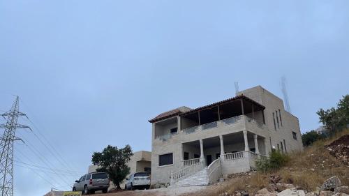 阿杰隆Furnished house بيت مفروش ابو فارس的山丘上的建筑,前面有汽车停放