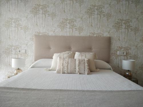 桑亨霍Chalet con vista a las Islas Cíes的卧室配有白色的床、枕头和壁纸