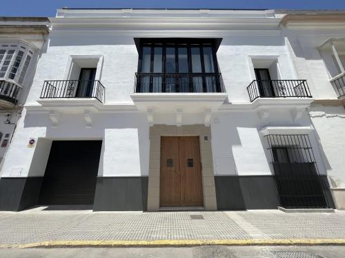 桑卢卡尔-德巴拉梅达CAMASanlúcar的白色的建筑,设有木门和两个阳台