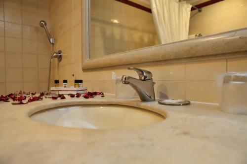 Martinchel西格勒多斯德谷曼索酒店的浴室的盥洗盆,在柜台上摆放着红色的鲜花