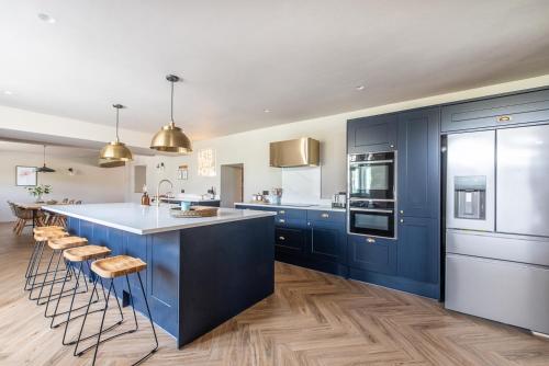 沃明斯特Immaculate 6 Bed House - Unique Cellar Bar- Airbnb的一间设有蓝色橱柜的厨房和一个带凳子的厨房岛