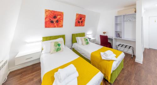 圣马丁格恩西圣湾酒店的一间卧室配有两张带黄白色床单的床